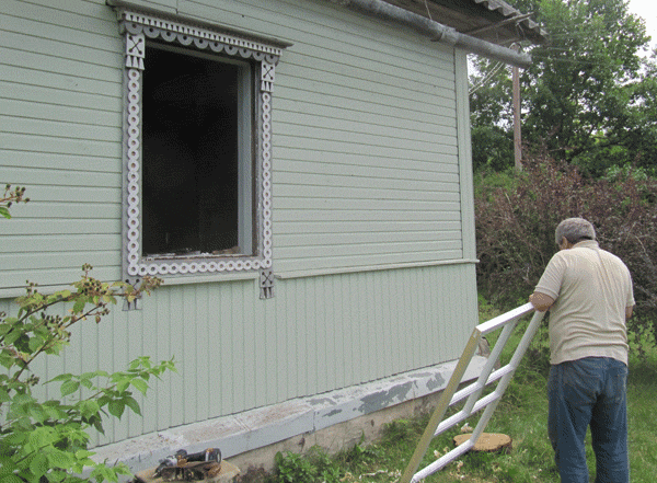 Открытый голый оконный проём, после демонтажа старого окна. Мастер подготавливает раму к установке. 