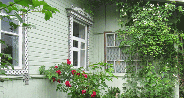 Фрагмент деревенского дома с установленными новыми окнами. Видна часть крыльца, остеклённая верандными рамами. 