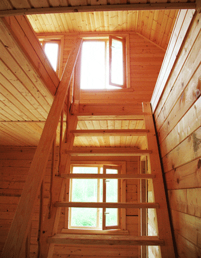 Деревянные окна на первом и втором этажах дачного дома. Фото через лестницу